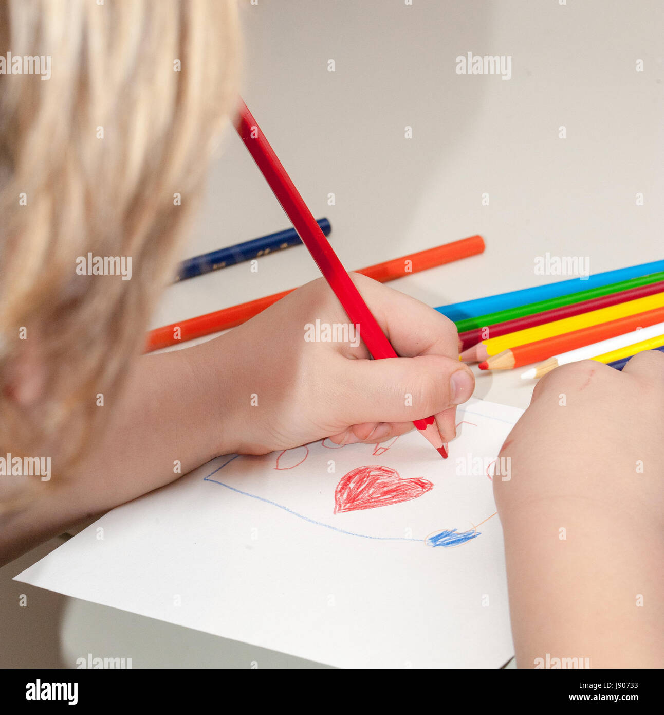 A child drawing with crayons and white paper Stock Photo - Alamy