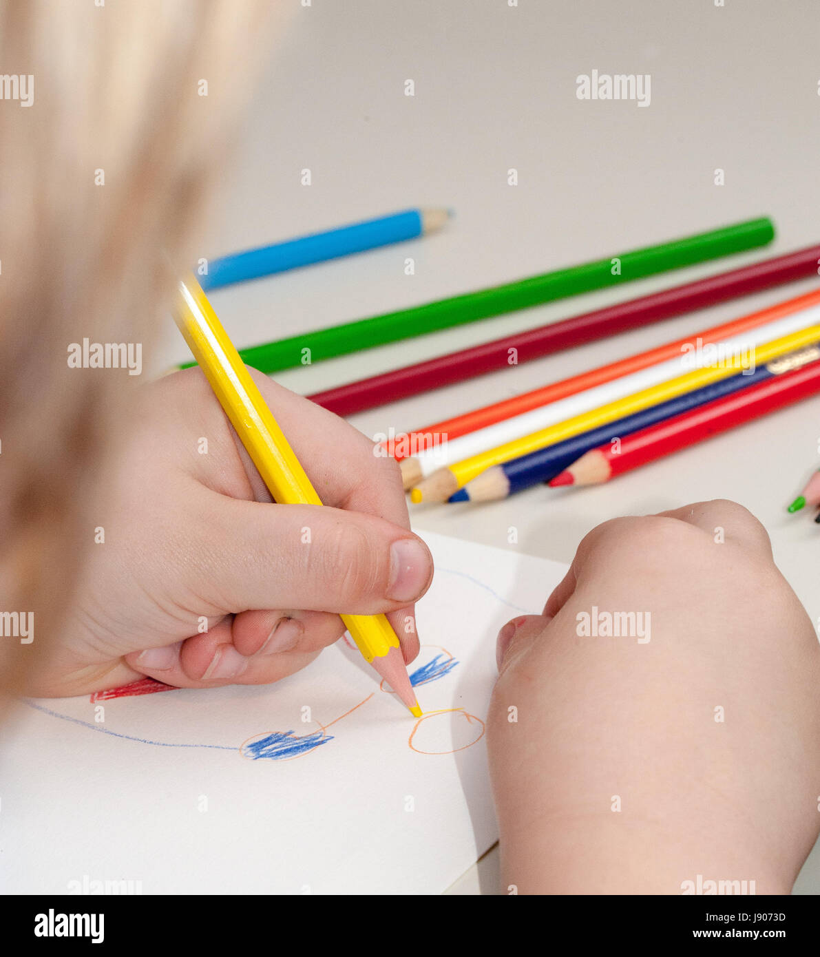 A child drawing with crayons and white paper Stock Photo - Alamy