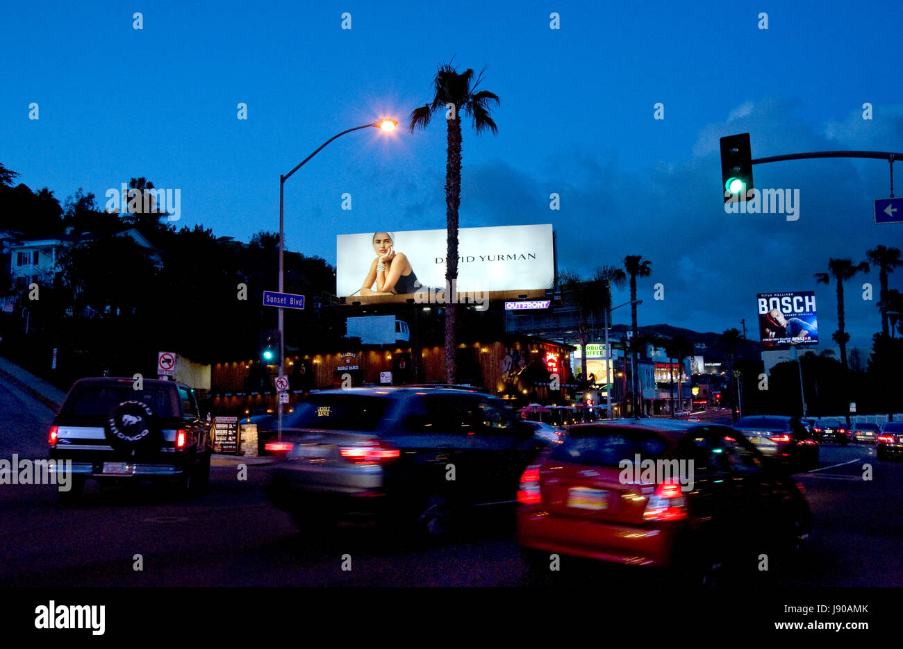 A fashion billboard lit up at dusk over traffic on the Sunset Strip in the west Hollywood neighborhood of Los Angeles, CA Stock Photo