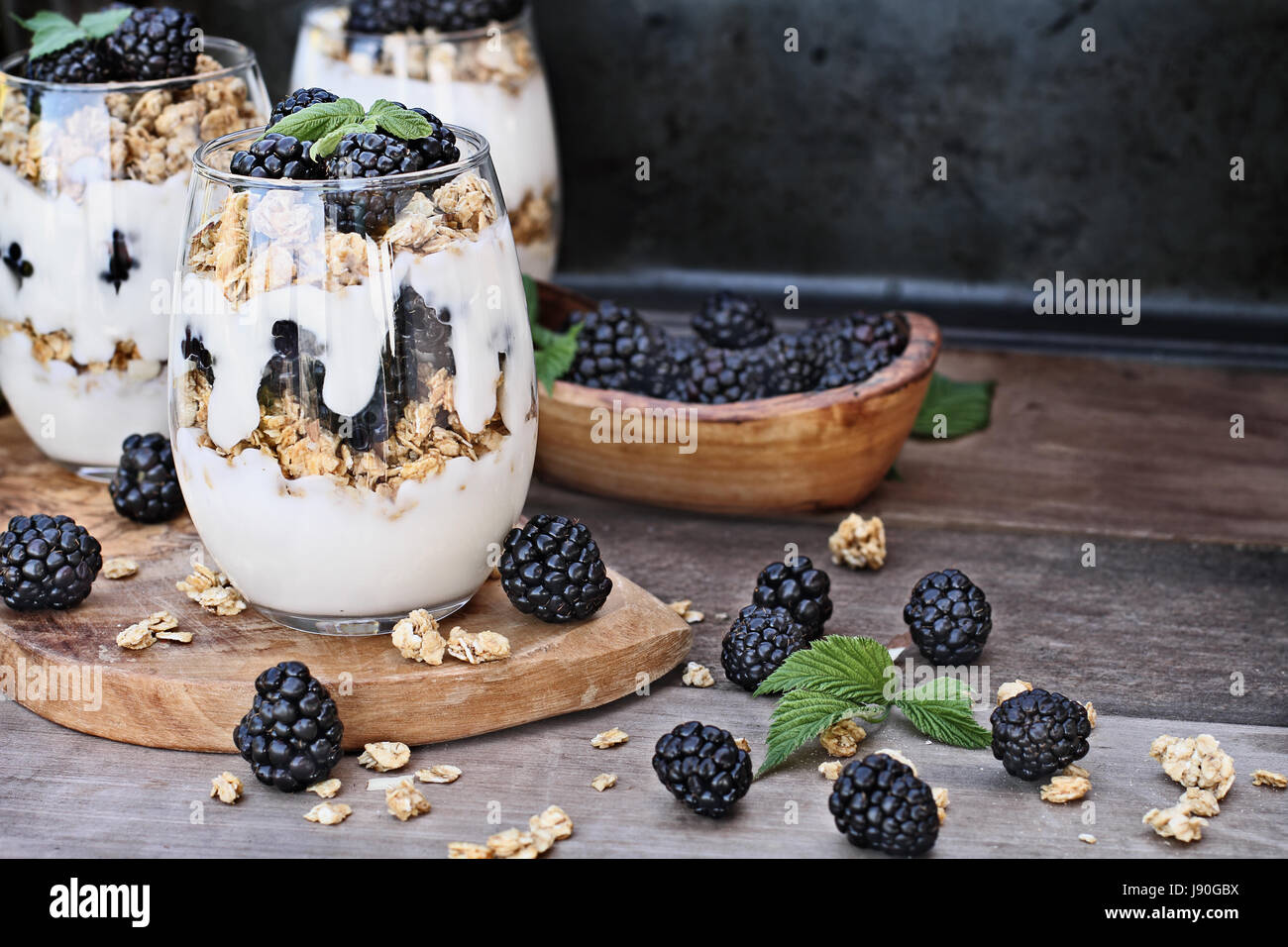 Blackberry parfaits made with Greek yogurt, granola and fresh blackberries. Extreme shallow depth of field with selective focus on parfait in foregrou Stock Photo