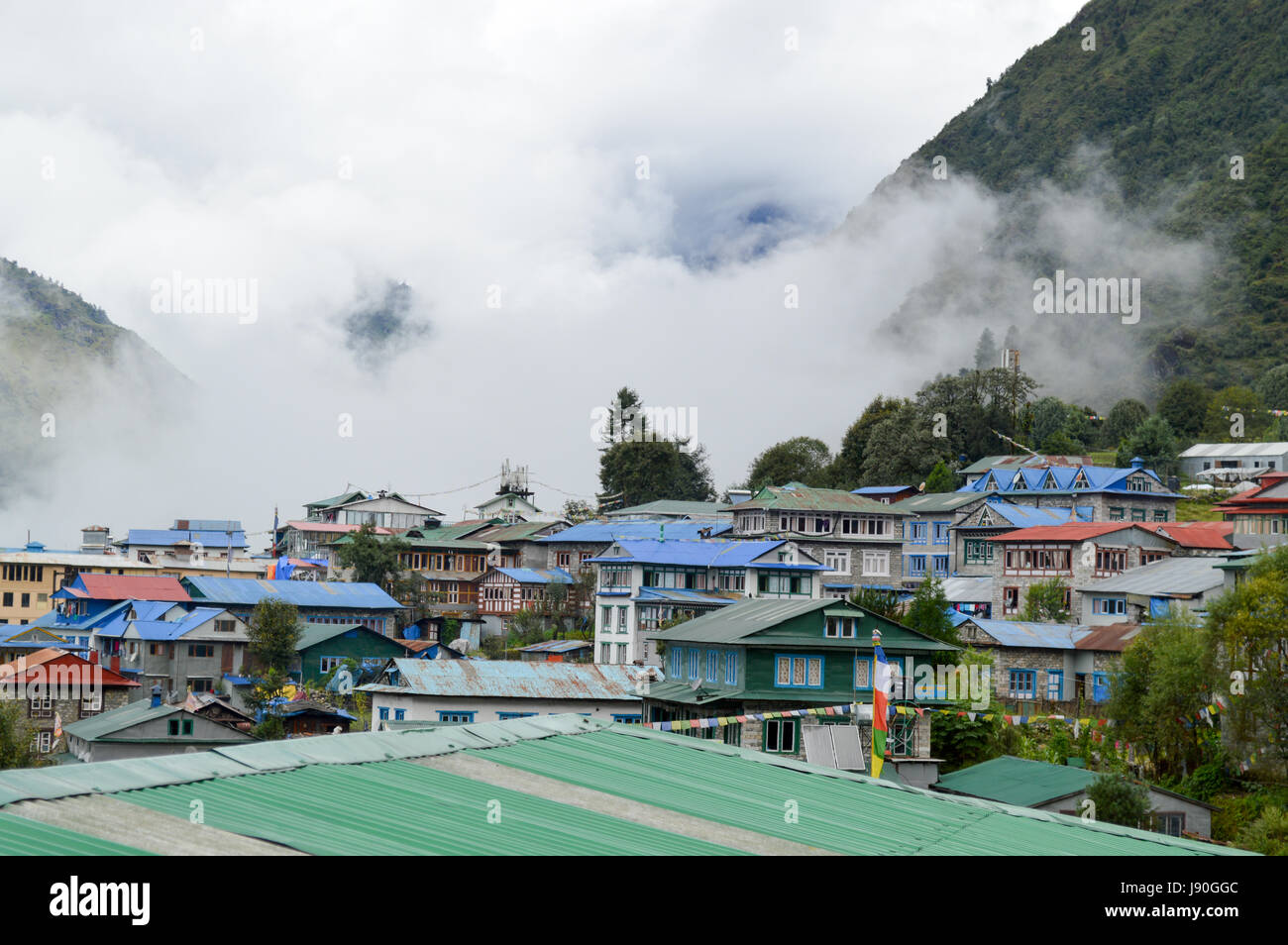 Lukla, Nepal. Beautiful rooftop view of the houses between the mountains and the clouds in Lukla, Nepal. Stock Photo