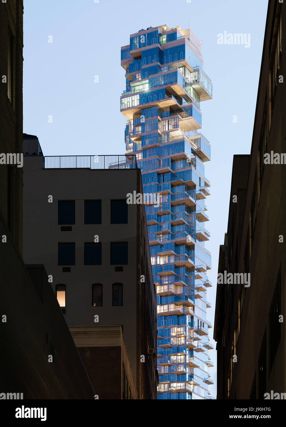 A high-rise luxury tower seen from a narrow alley in Tribeca at dusk. 56 Leonard Street, New York, United States. Architect: Herzog + de Meuron, 2017. Stock Photo