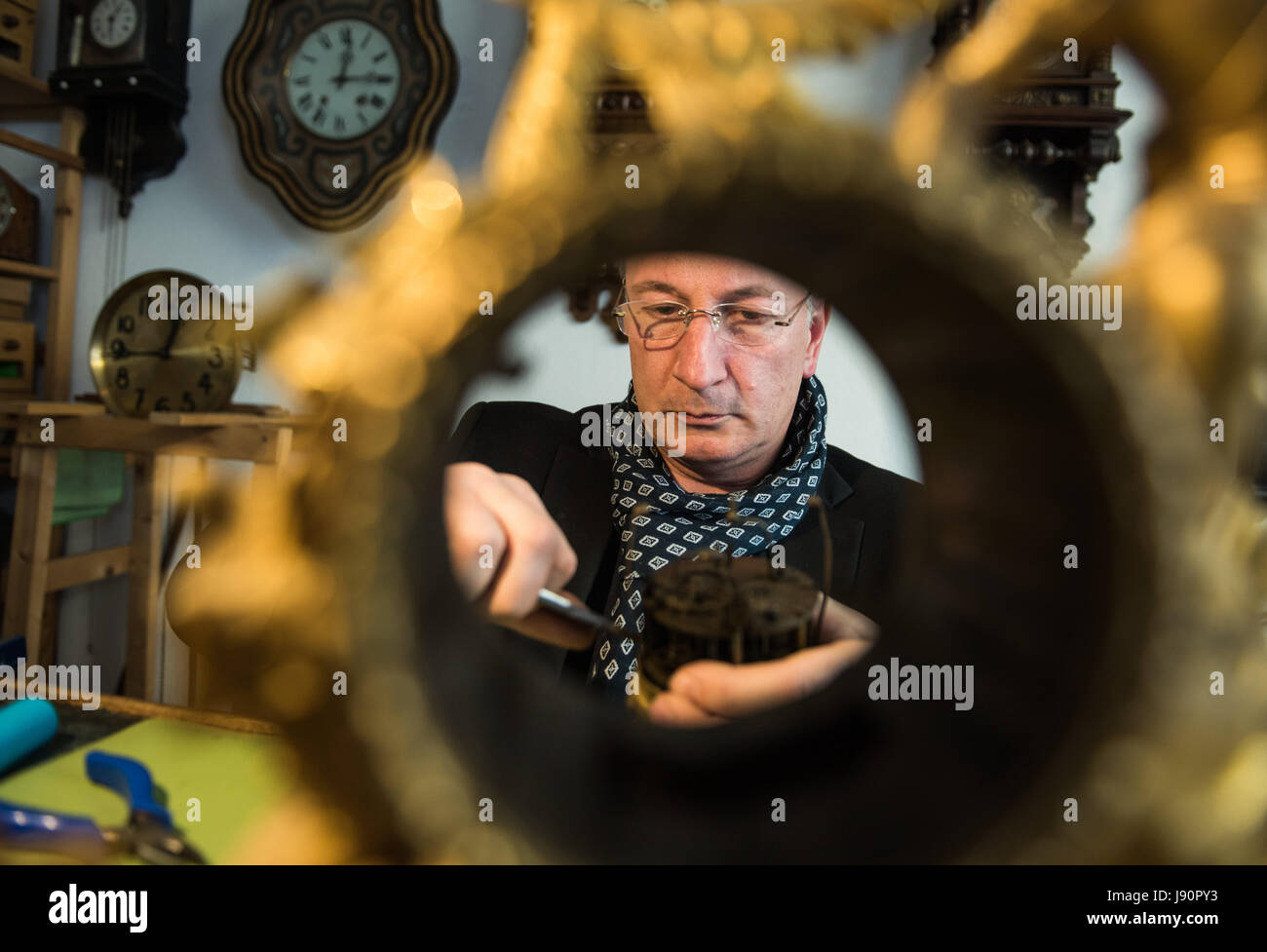 Mainz, Germany. 08th May, 2017. Picture of Dietmar Koester - taken through an empty clock casing - as he reapis a clockwork in his workshop in Mainz, Germany, 08 May 2017. The man from Mainz is a skilled clock maker and specializes in the repair and restoration of old clocks. Photo: Andreas Arnold/dpa/Alamy Live News Stock Photo