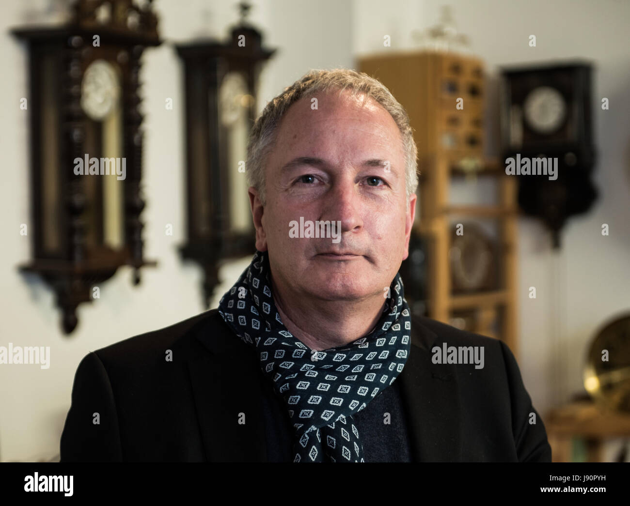 Mainz, Germany. 08th May, 2017. Dietmar Koester stands in front of old clocks in his workshop in Mainz, Germany, 08 May 2017. The man from Mainz is a skilled clock maker and specializes in the repair and restoration of old clocks. Photo: Andreas Arnold/dpa/Alamy Live News Stock Photo