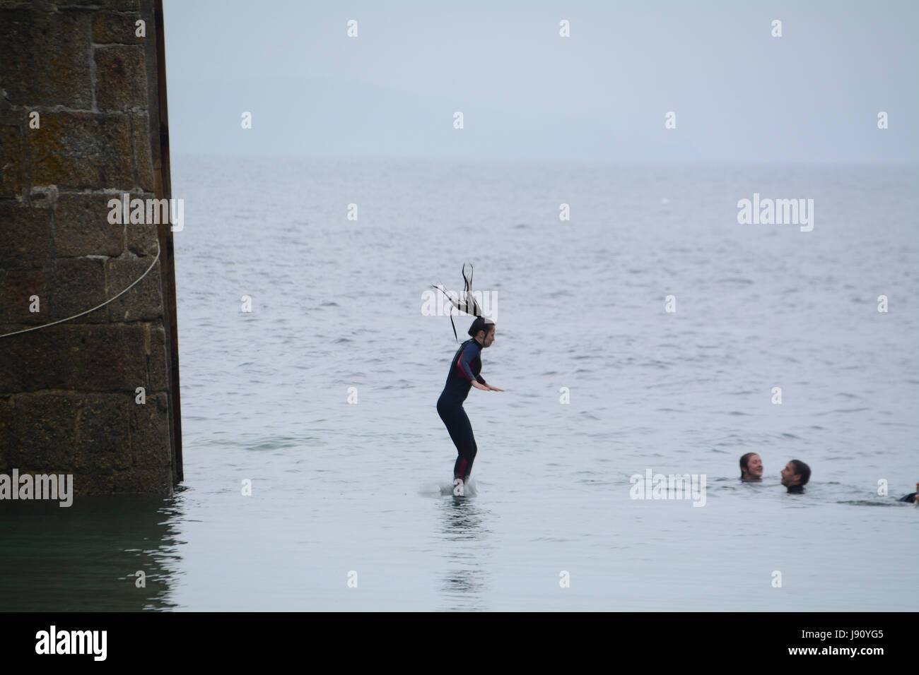 Mousheole Harbour, Cornwall,UK. 31st May 2017. UK Weather. After a misty start to the day, the weather is getting warmer on the Cornish coast, with families enjoying the beach, and people jumping off the harbour wall into the sea. Credit: cwallpix/Alamy Live News Stock Photo