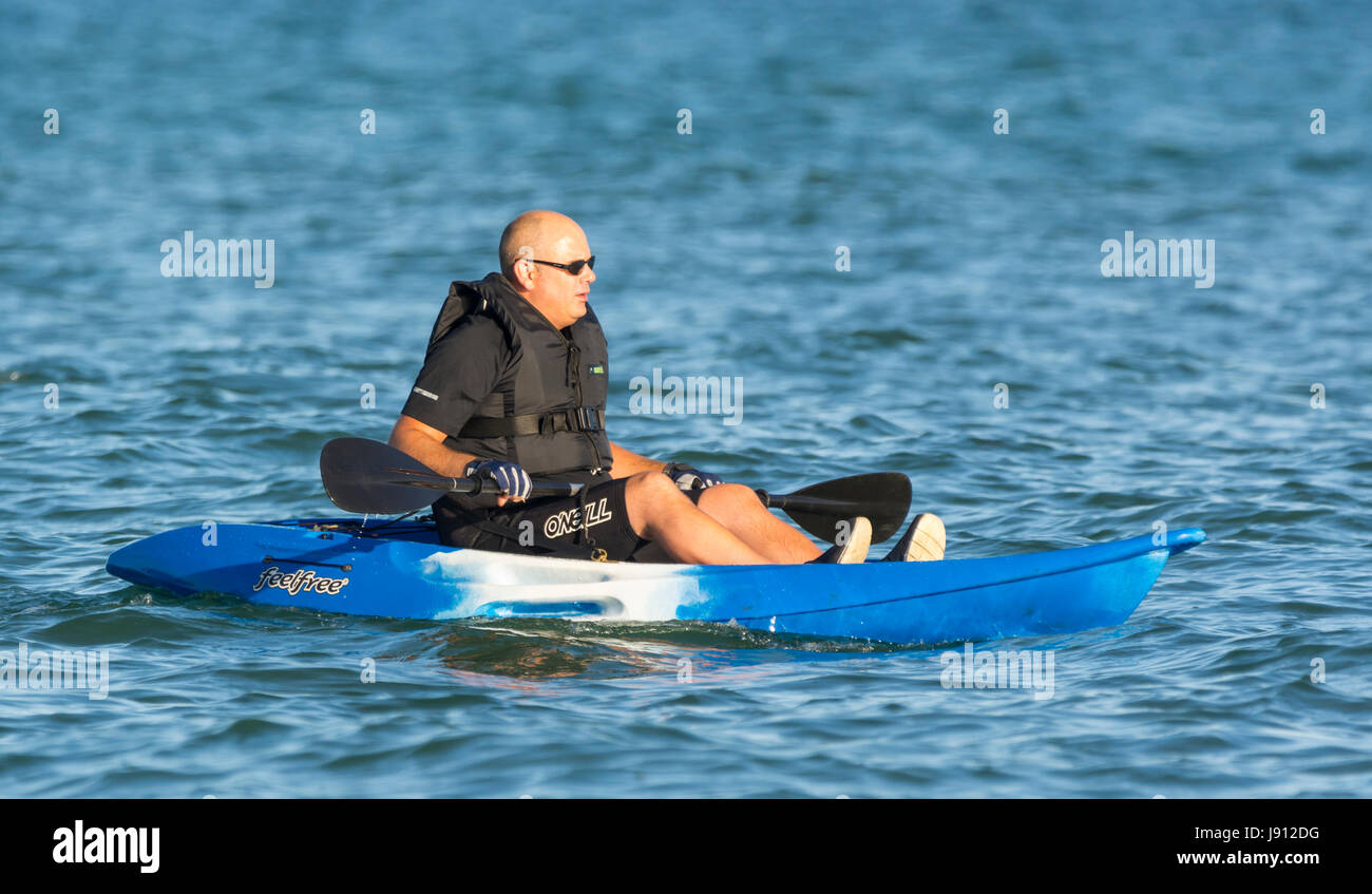Man kayaking on the sea near the shore on a hot day in Summer in the UK. Stock Photo
