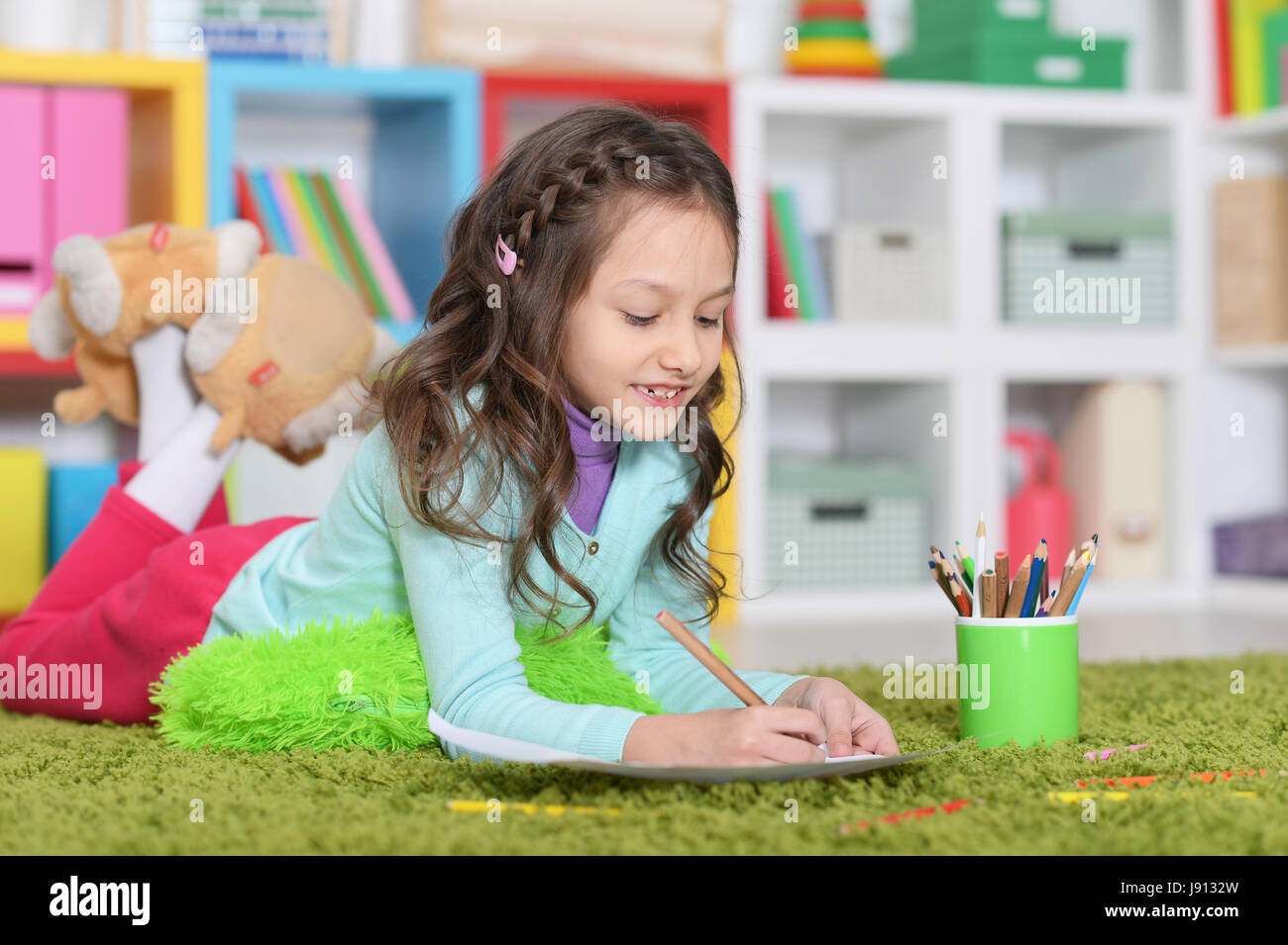 Little girl lying on floor and drawing picture Stock Photo - Alamy