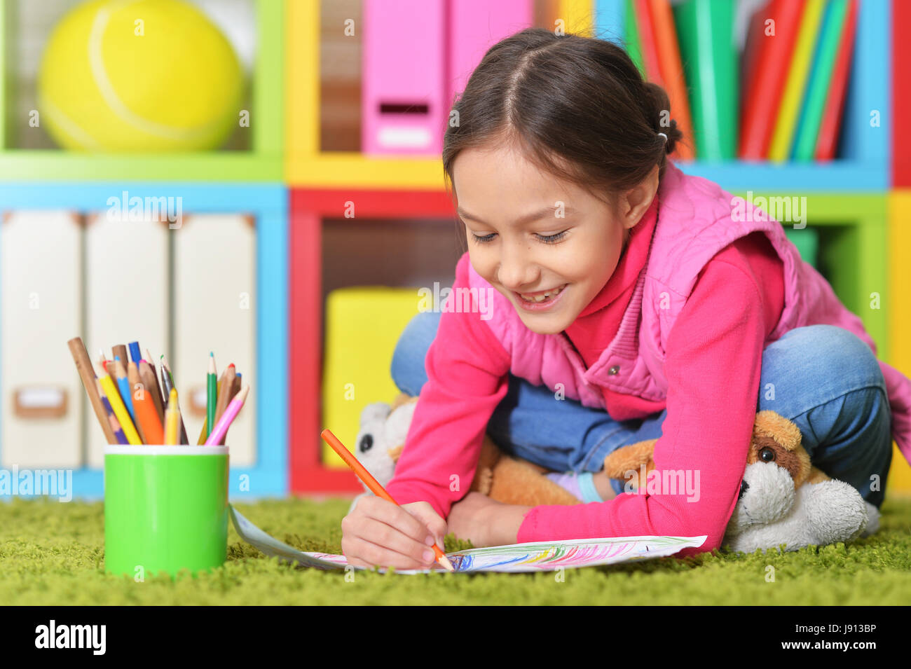 Cute little girl lying on floor and drawing picture Stock Photo - Alamy