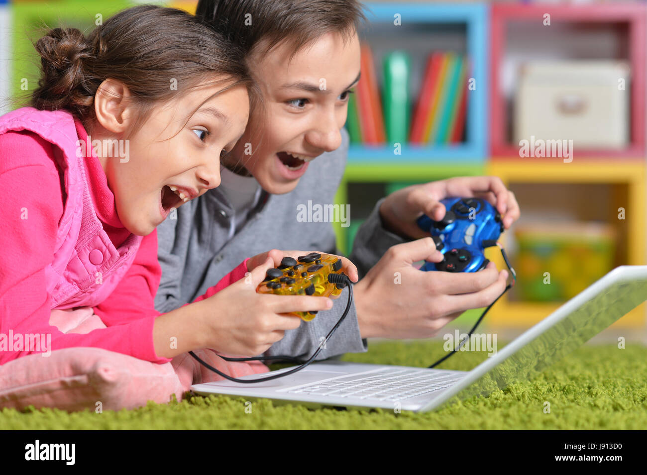 Excited brother and sister playing computer game with help of joysticks Stock Photo