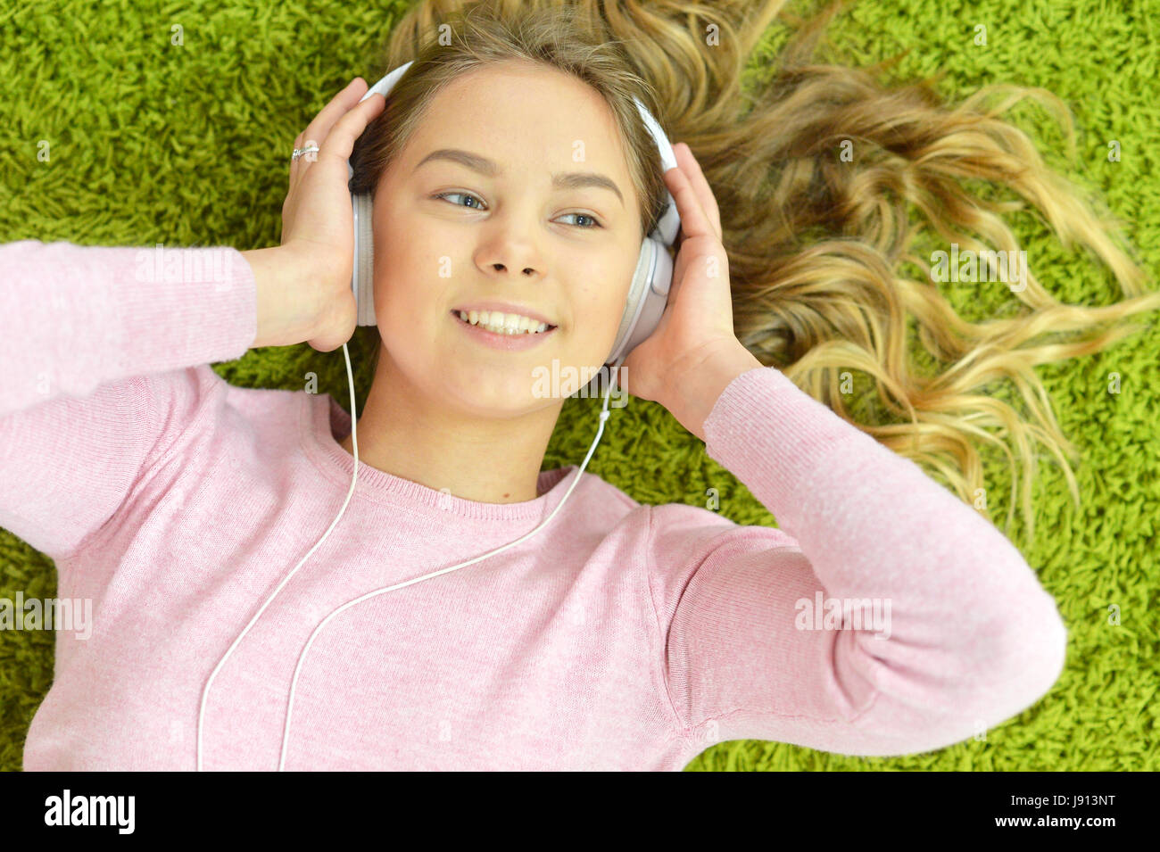 Pretty teen girl lies on the floor and listens to music Stock Photo - Alamy