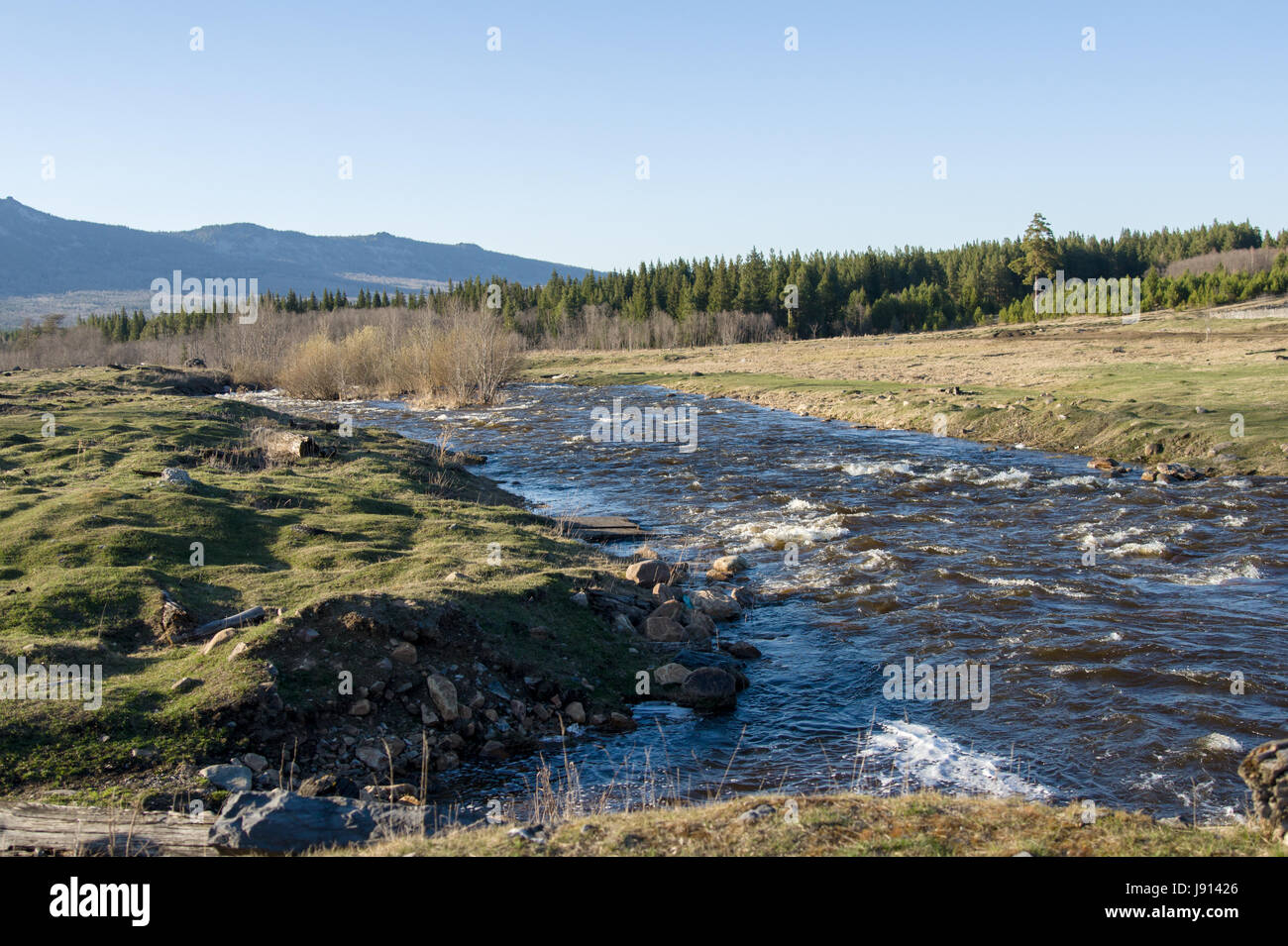 A rough mountain river flows next to the village Stock Photo - Alamy