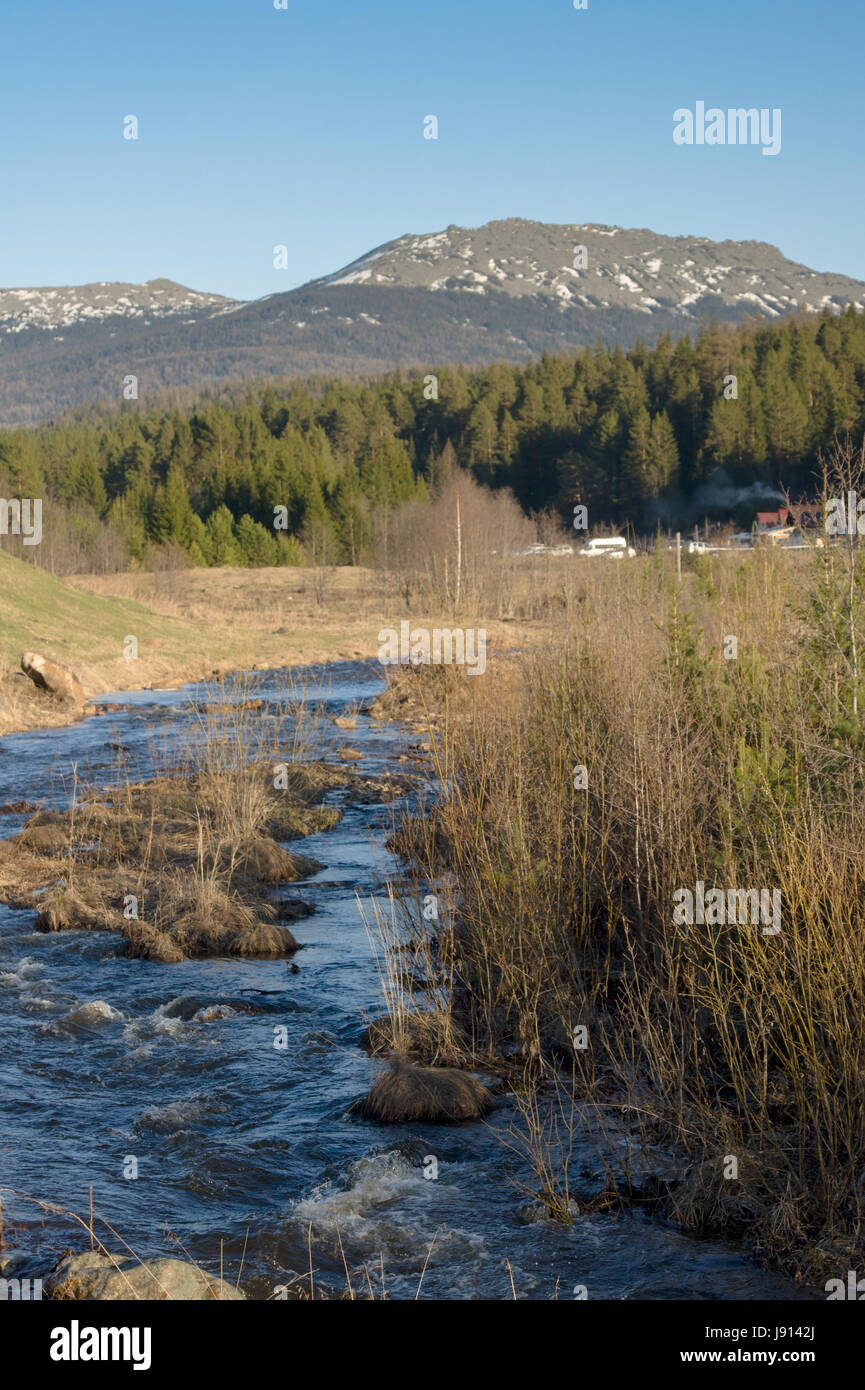 A rough mountain river flows next to the village Stock Photo - Alamy