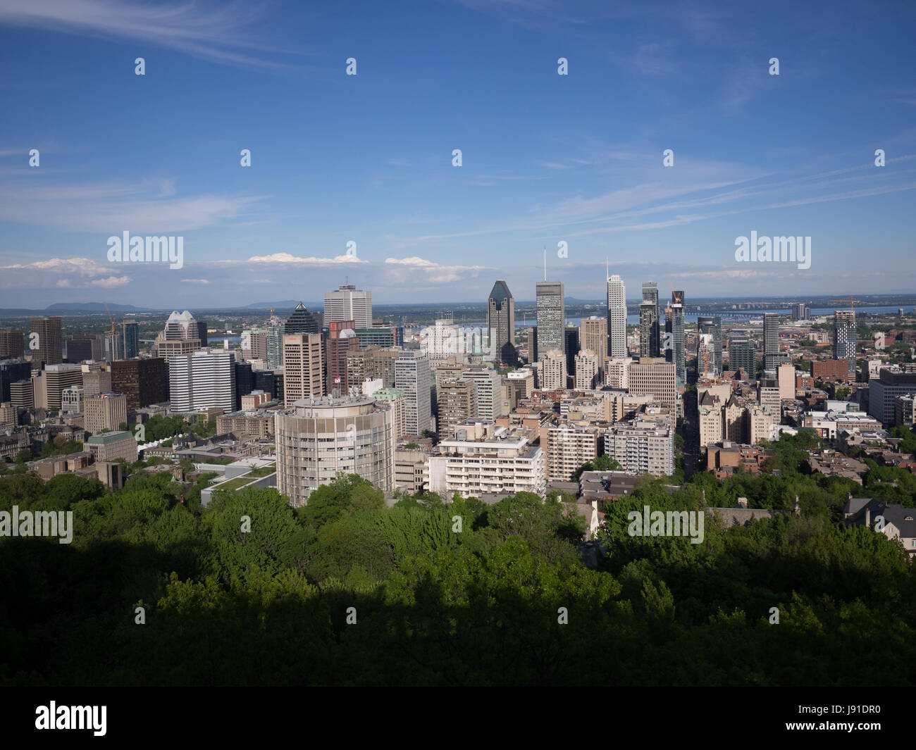 Montreal skyline during the day as viewed from Mount Royal Overlook. The summer time and clear blue skies add weight to an impressive Canadian Skyline Stock Photo