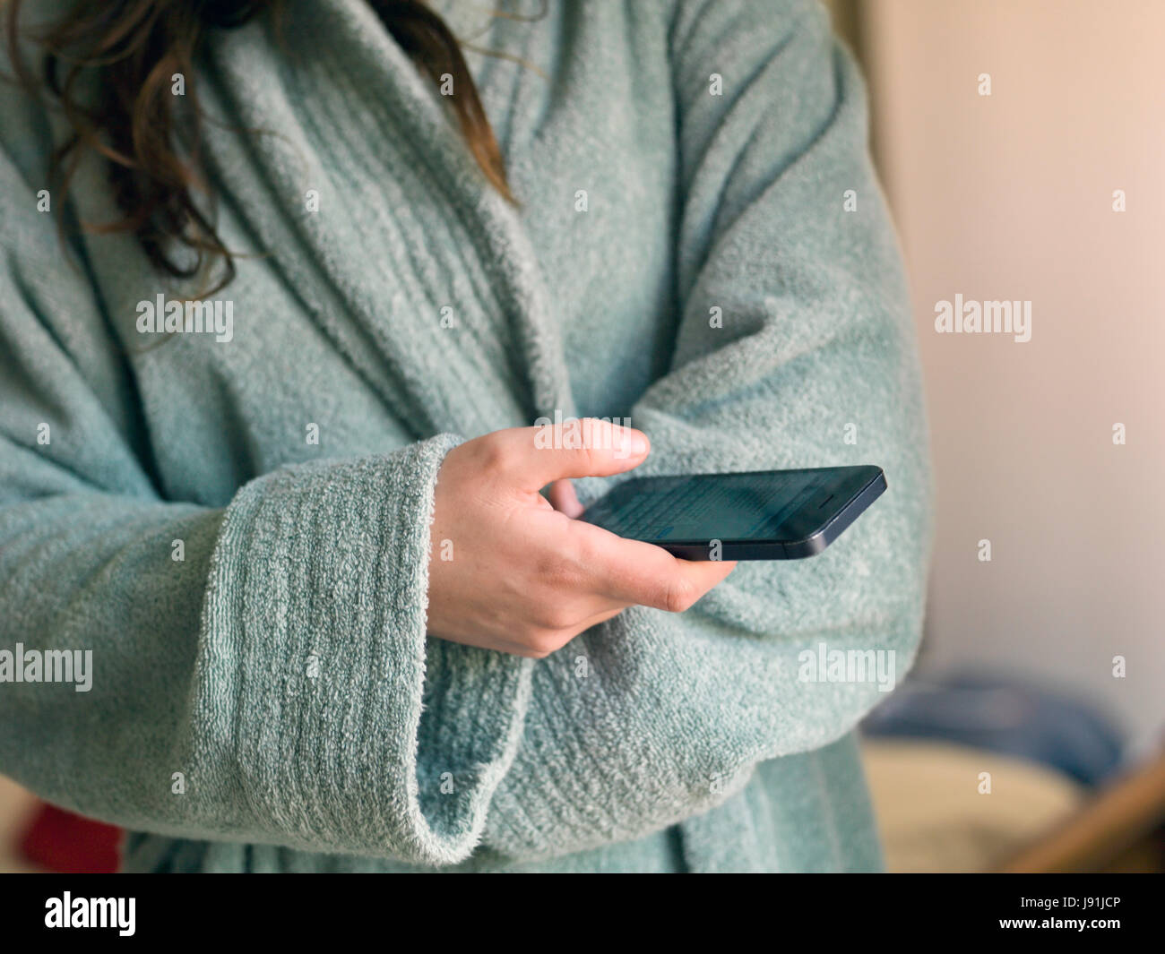 woman in dressing gown on mobile phone Stock Photo