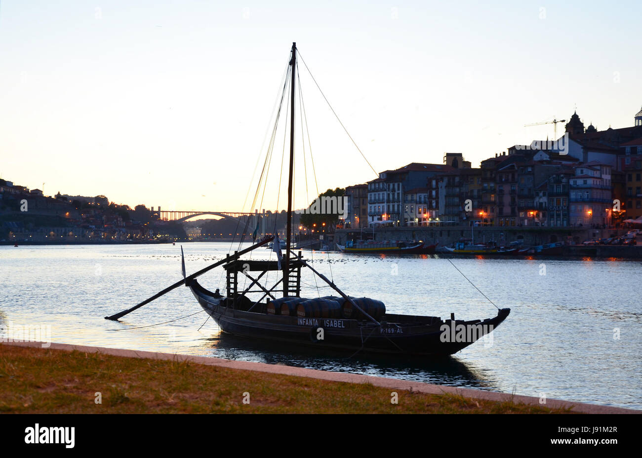 Traditional boat (Rabelo) with wine barrels at Rio Douro, with Porto skyline in background - Porto, Portugal Stock Photo