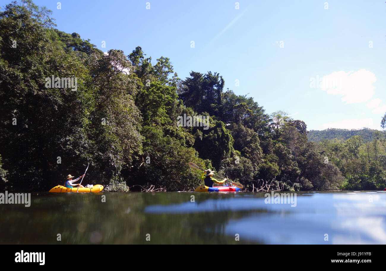 Couple paddling inflatable kayaks through rainforested Goldsborough Valley, Mulgrave River, near Cairns, Queensland, Australia. No MR or PR Stock Photo