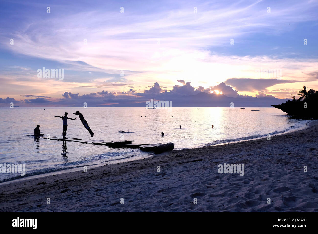 People bathing at sunset in the island of Siquijor located in the Central Visayas region of the Philippines Stock Photo