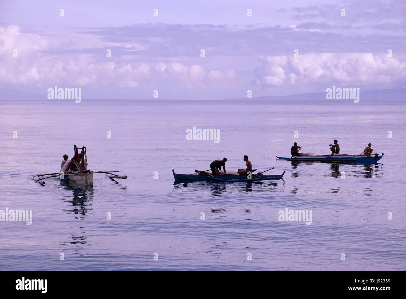 Fishermen in traditional banka outrigger boats in the island of Siquijor located in the Central Visayas region of the Philippines Stock Photo