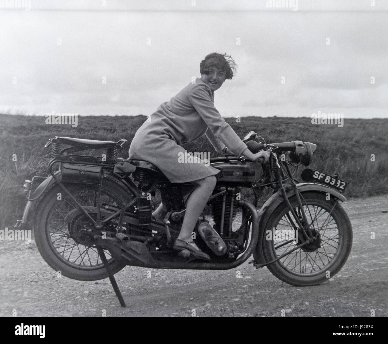Vintage photo of a woman sitting on a vintage motor cycle in the 1920s. Stock Photo