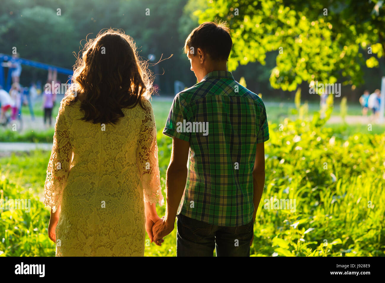 Young couple walking together hand by hand in park, rear view Stock ...