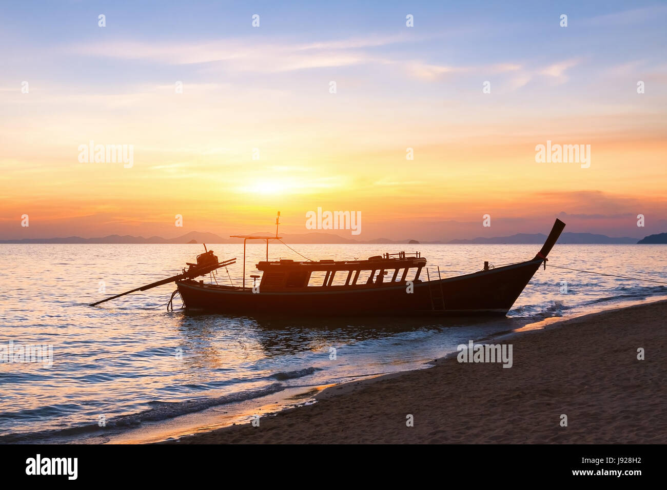 Silhouette of a traditional long-tail boat used to transport tourists at the beach at sunset, Krabi, Thailand Stock Photo
