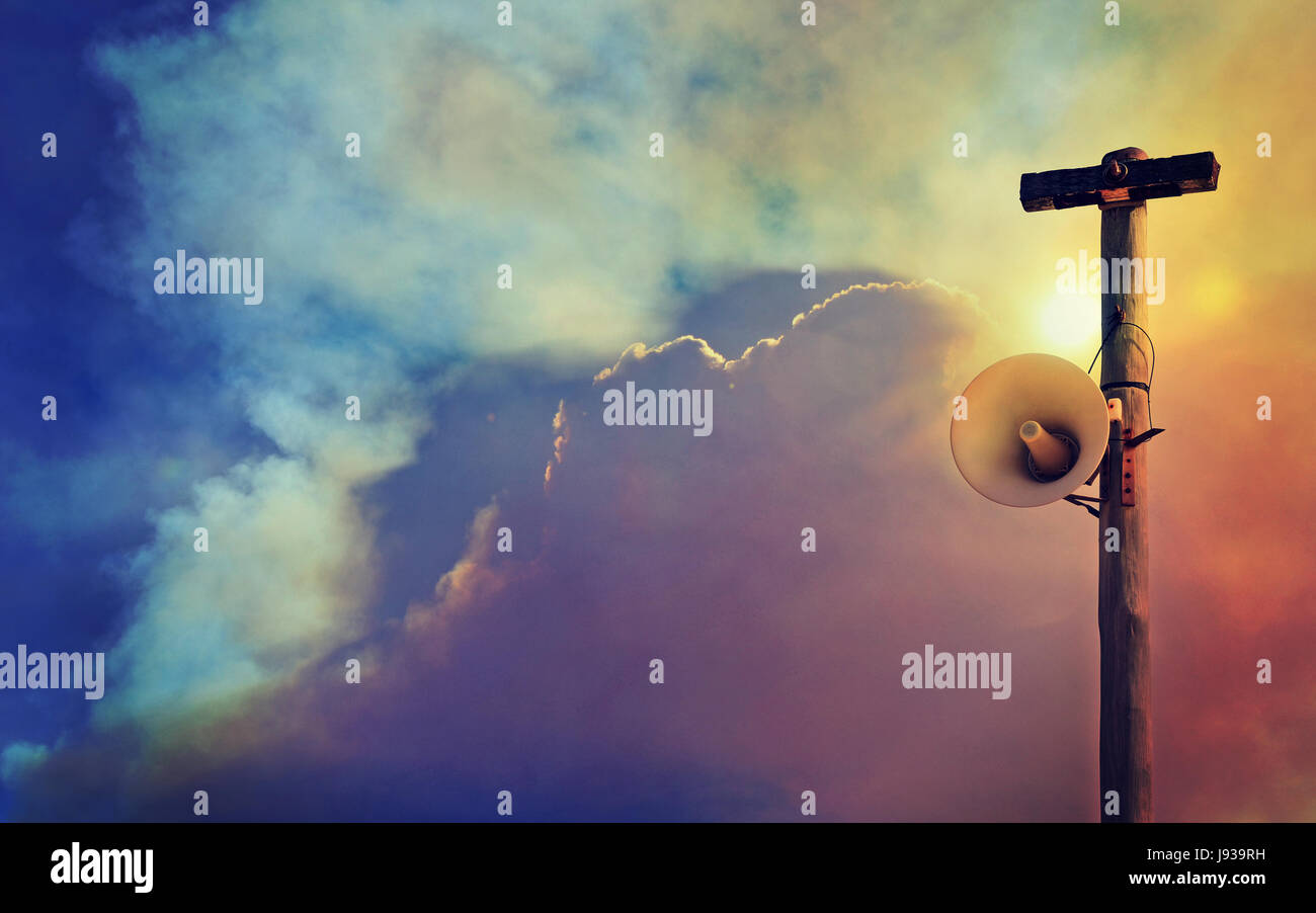 Outdoor loudspeaker warning system on telegraph pole against a smoke filled sky background. Copy space for text. Danger, emergency, disaster concepts Stock Photo
