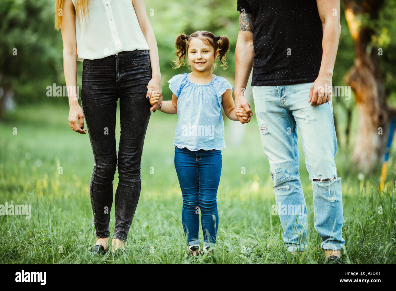 Excited young girl holding hands while walking with parents in park Stock Photo