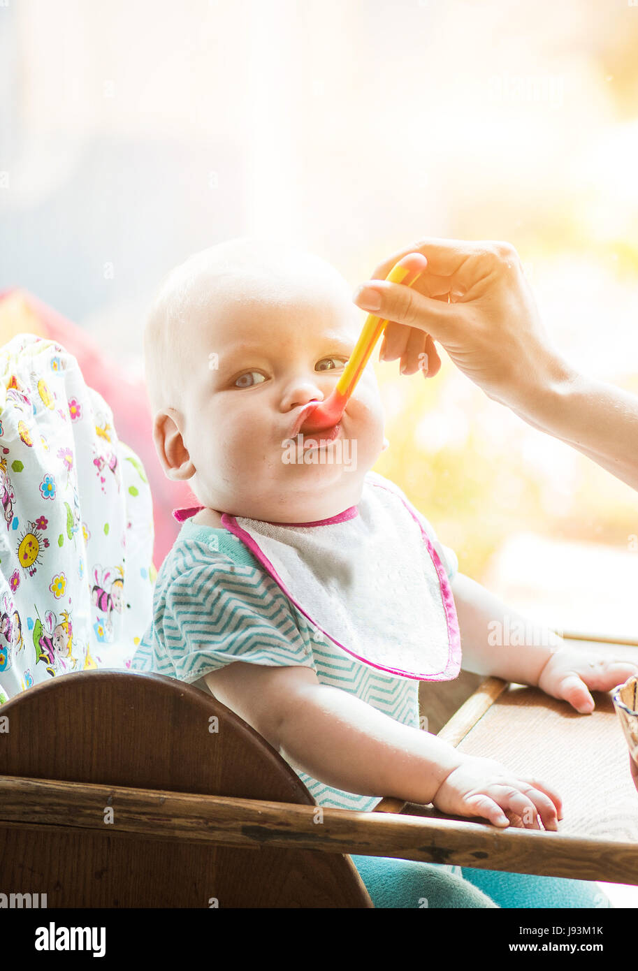 mother feeds funny baby from a spoon Stock Photo