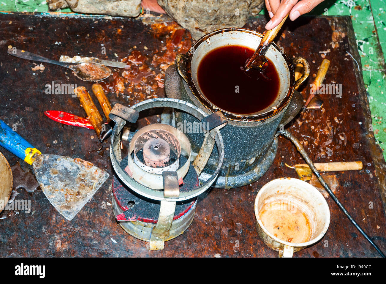 Melted wax in a bowl with brushes and other equipment to make traditional batik Stock Photo