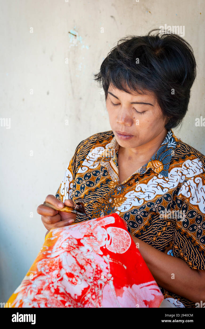 YOGYAKARTA, INDONESIA - SEPTEMBER, 15: Indonesian woman applying vax on batik in workshop. Batik is traditional art made by applying vax and dye on fa Stock Photo