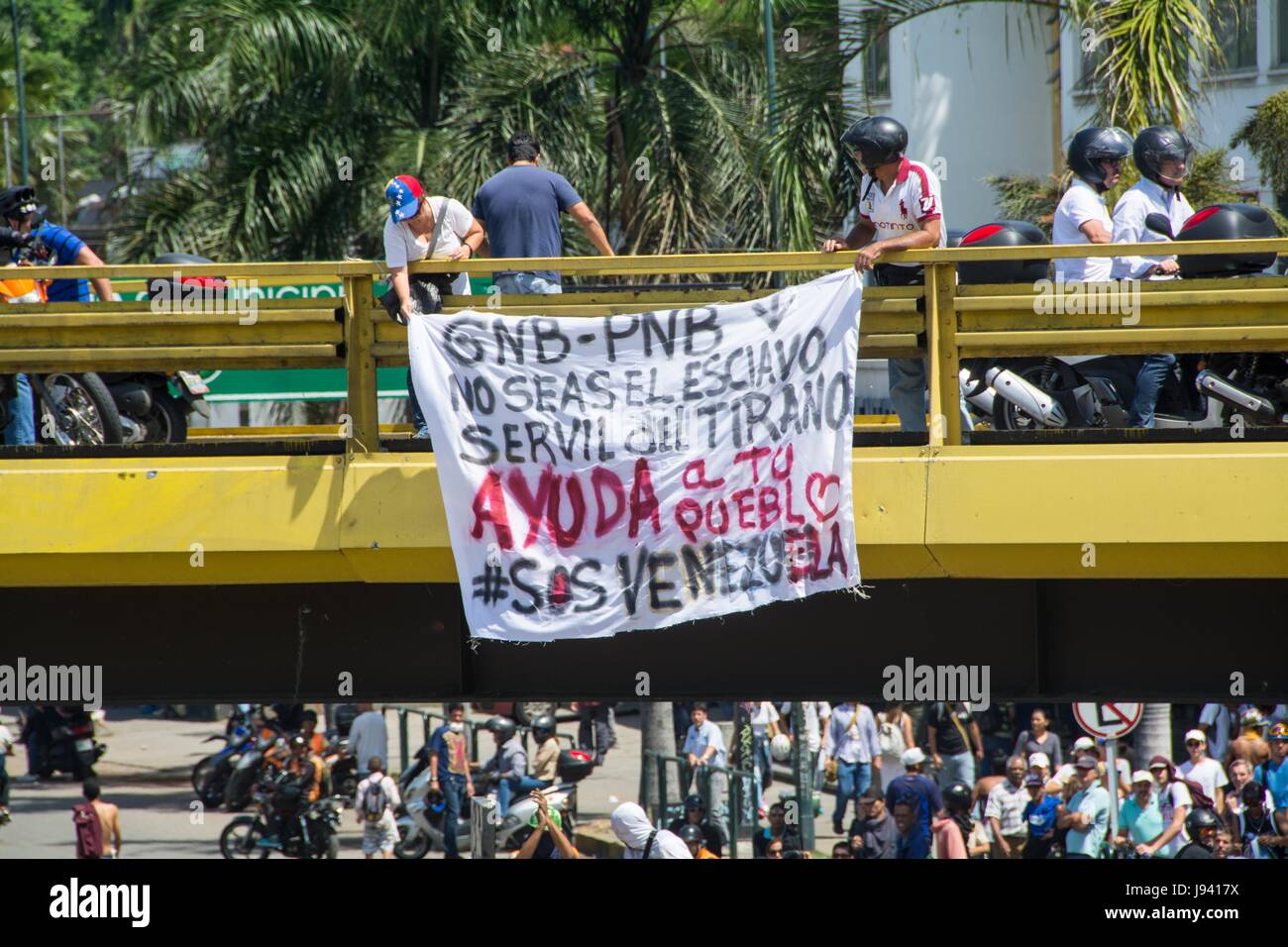A group of opponents place a sign on a bridge over Las Mercedes. Opponents marched to the Ombudsman's Office, wearing white shirts and photographs of  Stock Photo