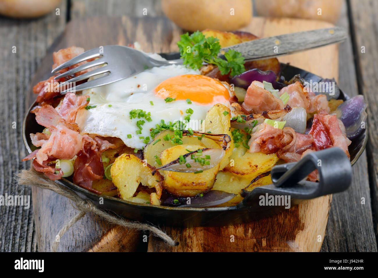 Farmer's breakfast with fried potatoes, fried egg and bacon served in an iron pan Stock Photo
