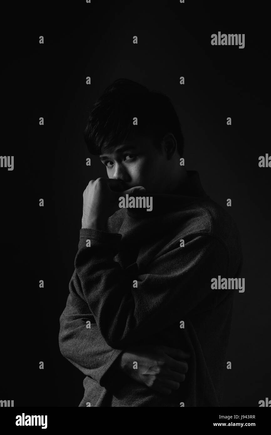 Young asian man's portrait against black background Stock Photo