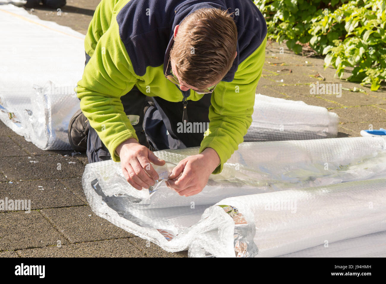 Worker cutting and taping insulation material on the street to be ready