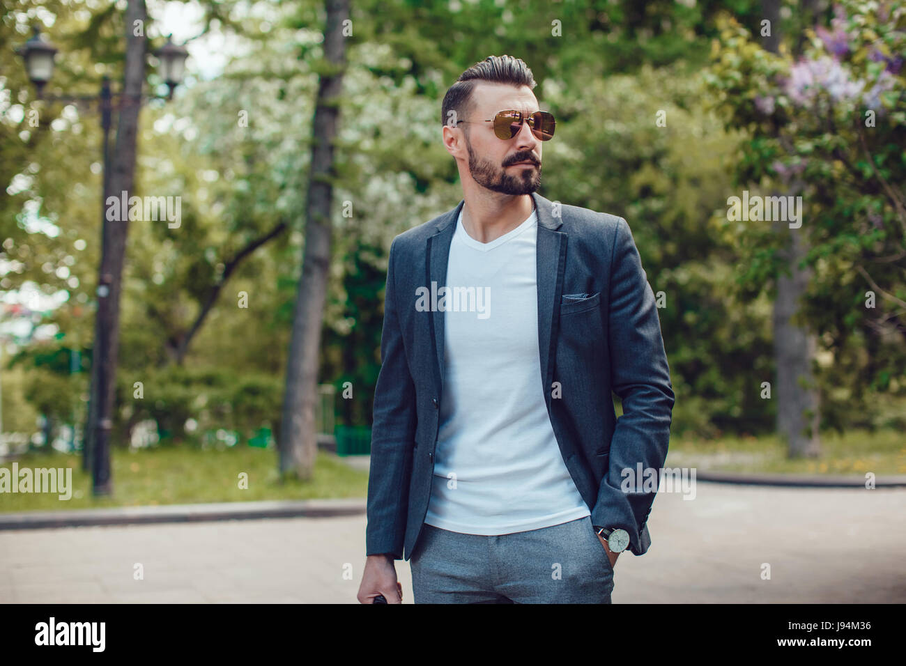 Stylish man with a beard and in sunglasses standing in the park Stock ...