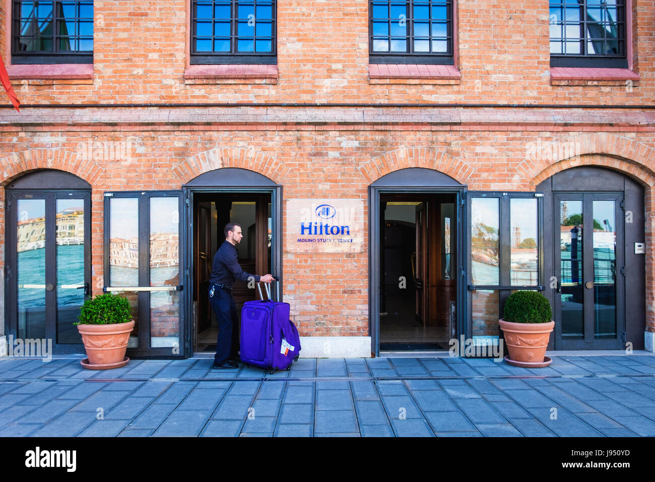 Venice, Giudecca. Luxury Hilton Molino Stucky hotel in restored flour mill  building, Bell hop with luggage,Five star accommodation Stock Photo