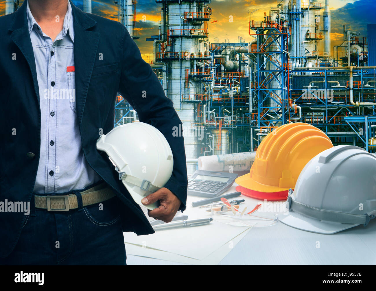 engineering man standing with white safety helmet against  oil refinery in petrochemical industry Stock Photo