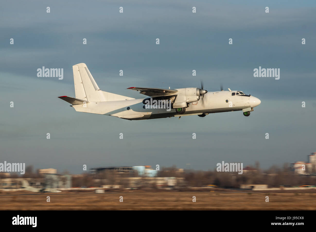 Old turboprop cargo plane is taking off from the airport on sunset ...