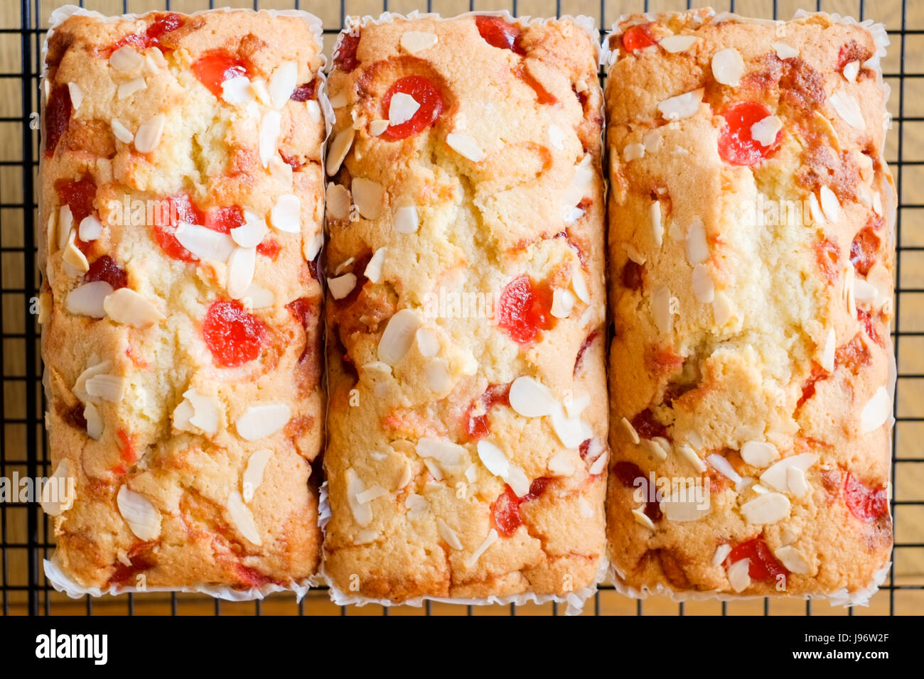 Home cooked food. Three cherry and almond cakes on a cooling rack. Stock Photo