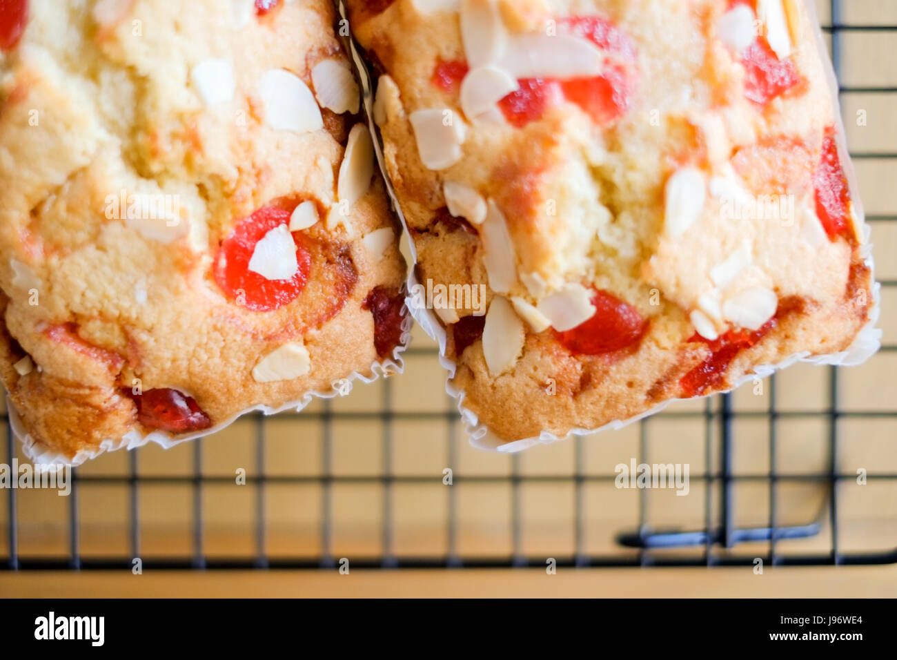 Home cooked food. Two cherry and almond cakes on a cooling rack. Stock Photo