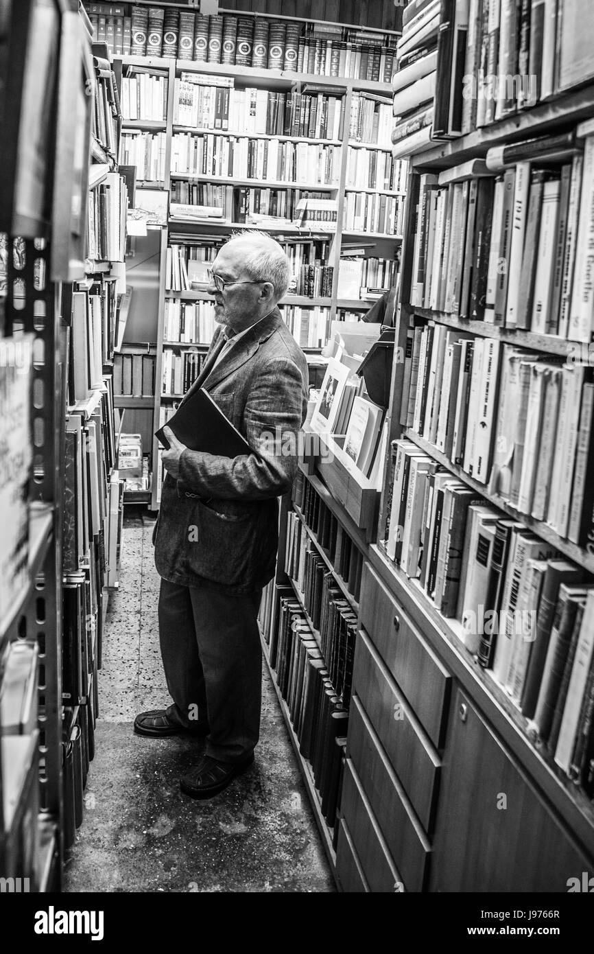 An old man looking for books in a secondhand or bookstore