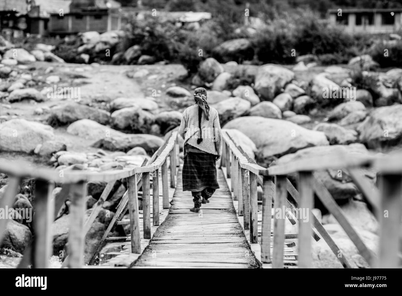 A older woman walking on a bridge in Manali, India. Stock Photo