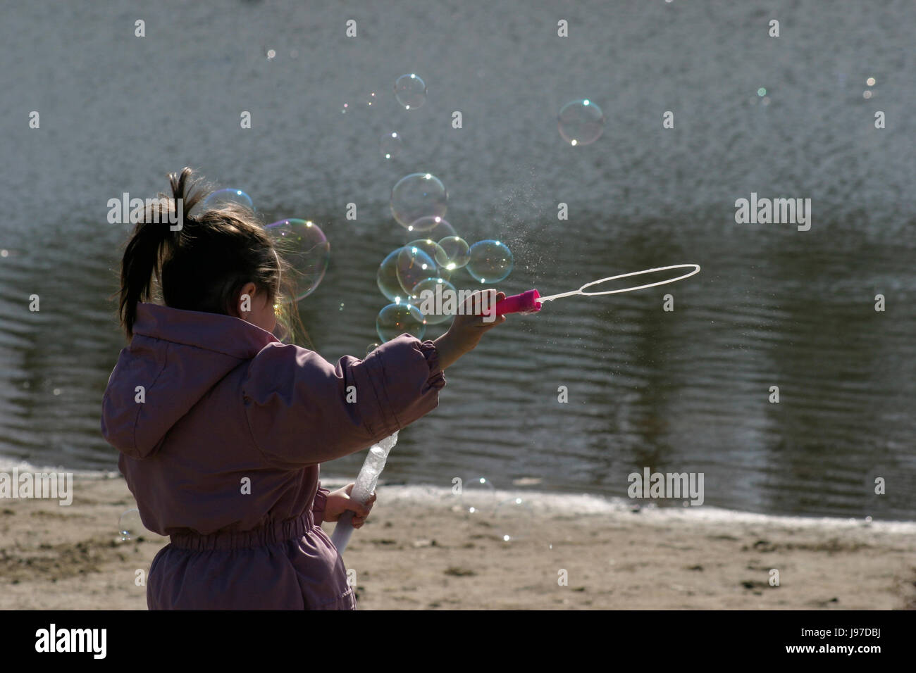 Little girl making soap bubbles by the lake using wand Stock Photo - Alamy