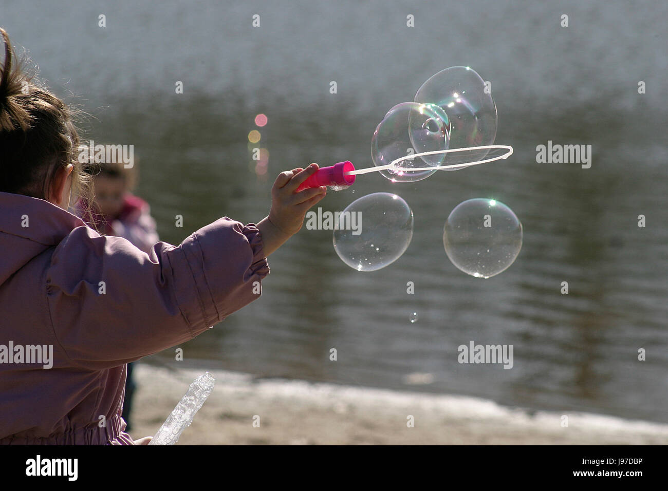 Little girl making soap bubbles by the lake using wand Stock Photo - Alamy