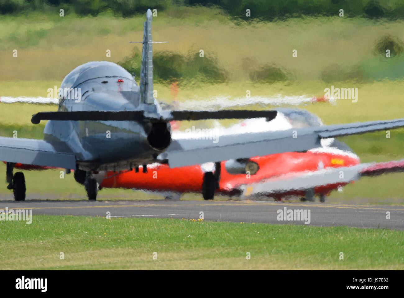 BAC Strikemaster following a Jet Provost T5 onto the runway, creating a heat haze of 'jelly air' from their combined exhausts. Space for copy Stock Photo