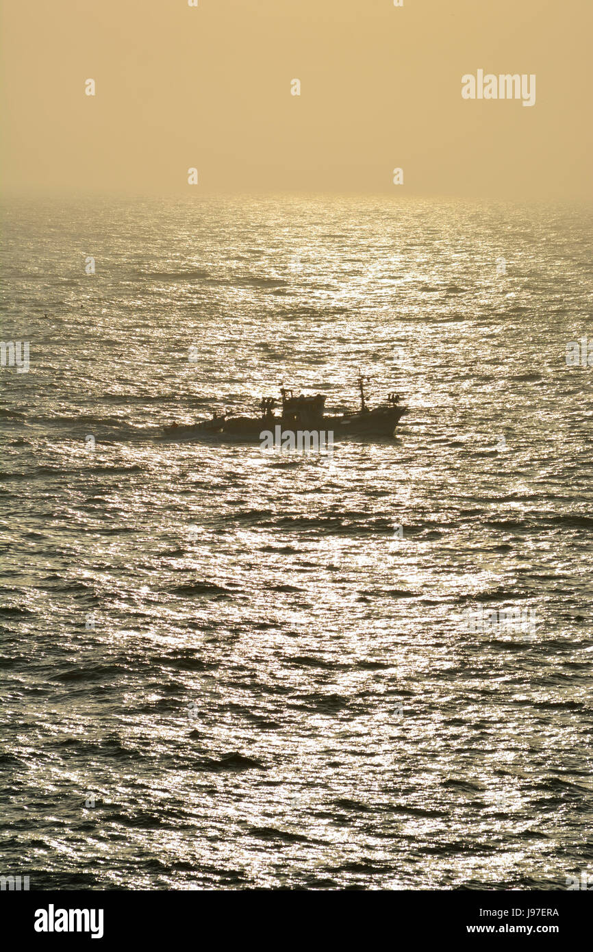 A traditional fishing boat (traineira) going out to the Atlantic Ocean at sunset. Peniche, Portugal Stock Photo