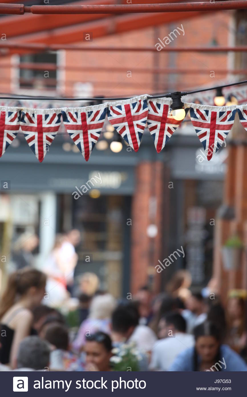 Rows of Union Jack flags and bunting hang from a roof on a building