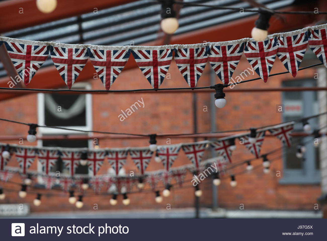 Rows of Union Jack flags and bunting hang from a roof on a building