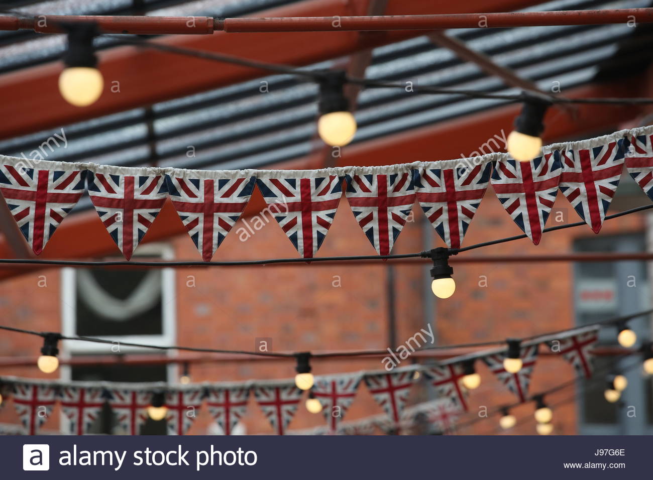 Rows of Union Jack flags and bunting hang from a roof on a building