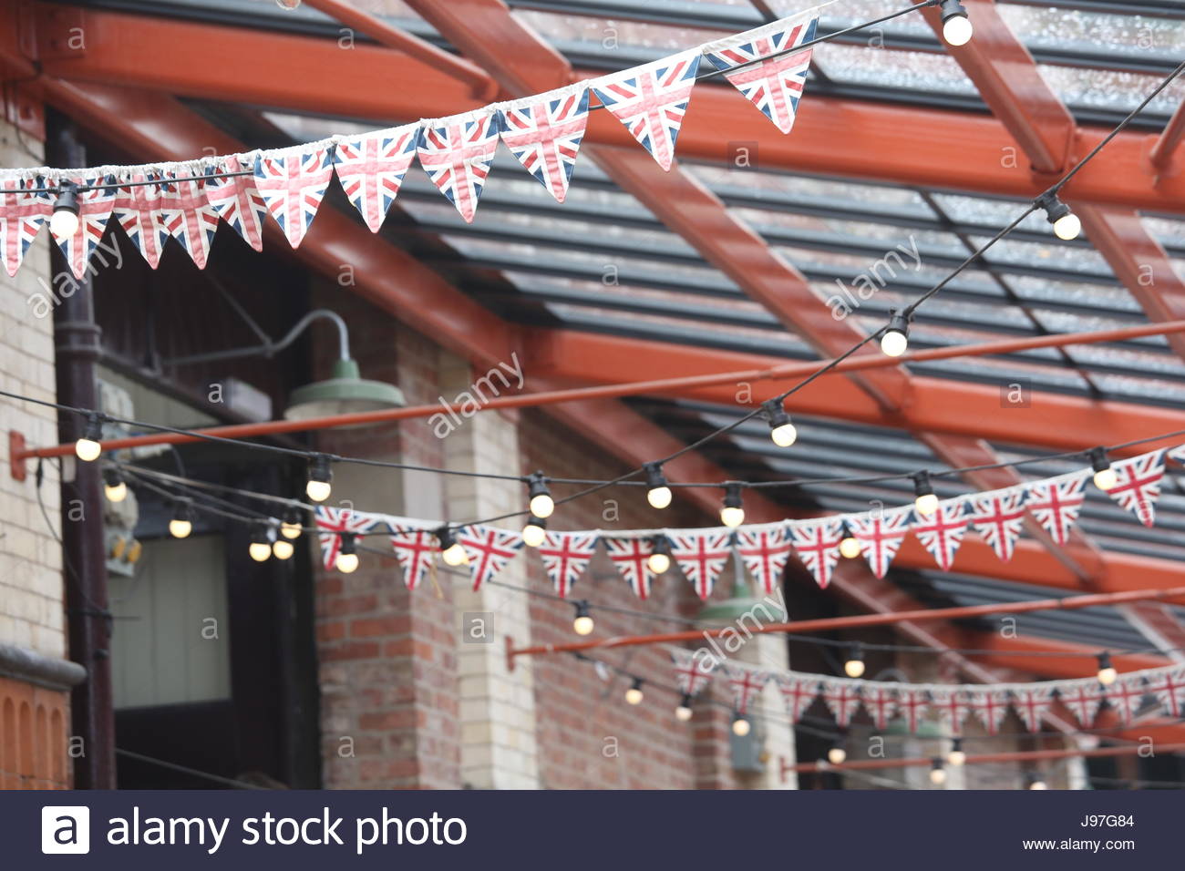 Rows of Union Jack flags and bunting hang from a roof on a building